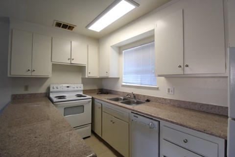 A kitchen with white cabinets and a window.
