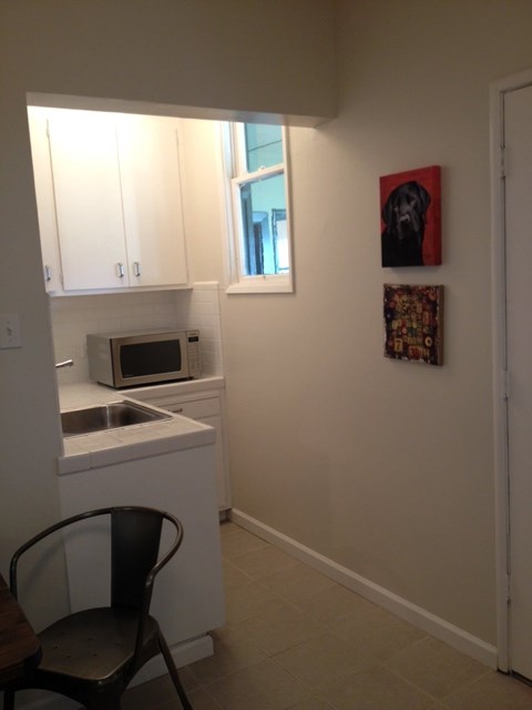A kitchen with a chair and a painting of a dog on the wall.