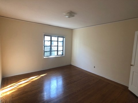an empty room with a window and wooden floors