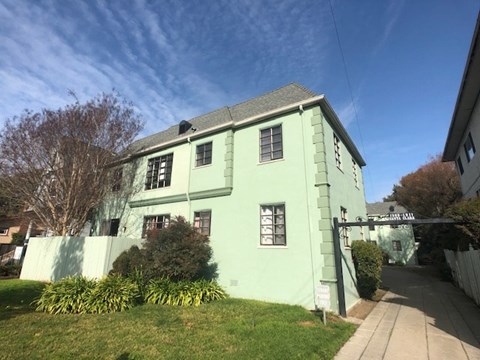 a green house with a sidewalk in front of it