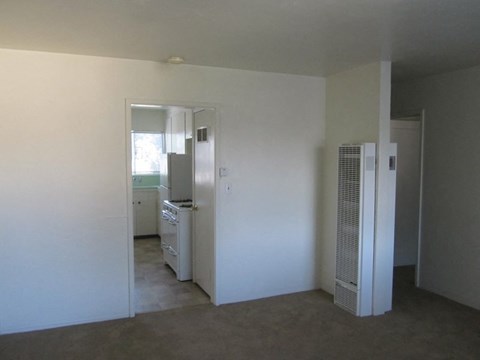 A white room with a kitchen in the background.