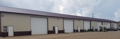 A large industrial building with a row of white garage doors.