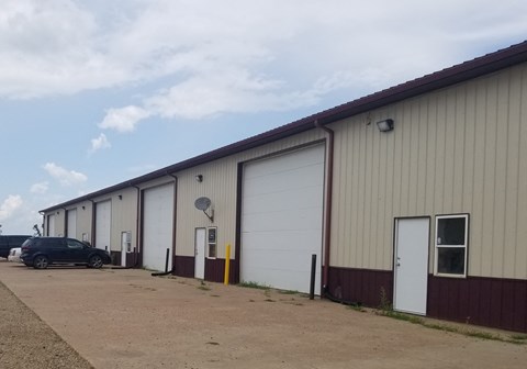A long building with a car parked in front.