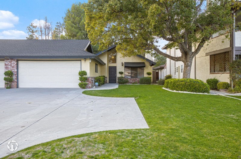A house with a driveway and a tree in front.
