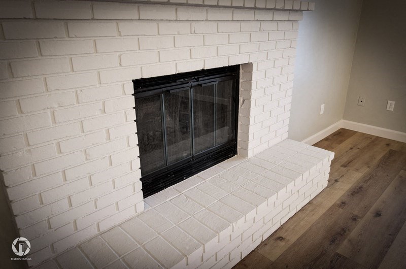 A white brick fireplace with a black grate.