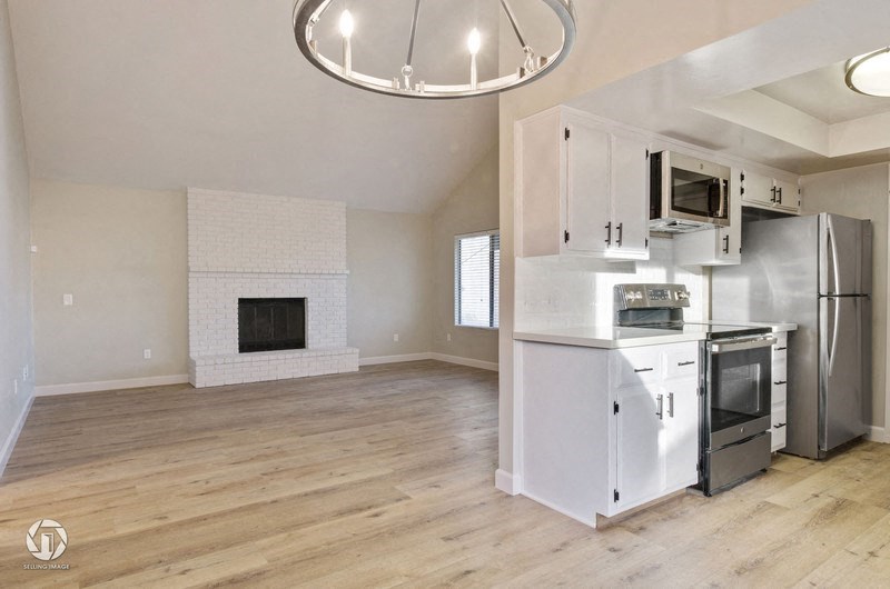A modern kitchen with a white fireplace and stainless steel appliances.