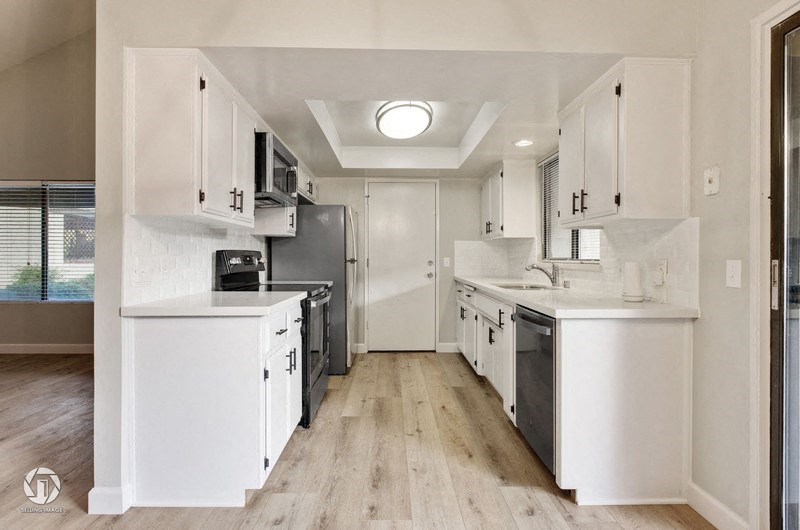 A modern kitchen with white cabinets and appliances.
