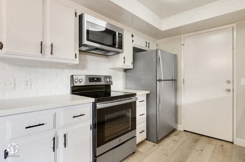 A kitchen with white cabinets and appliances.