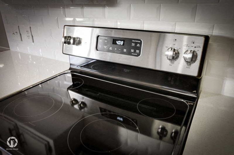A modern stainless steel oven with a digital control panel is installed in a kitchen.