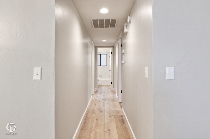 A long, narrow hallway with wooden floors and white walls.