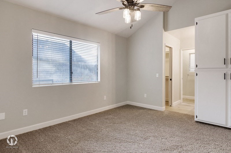 A room with a ceiling fan and a window with blinds.