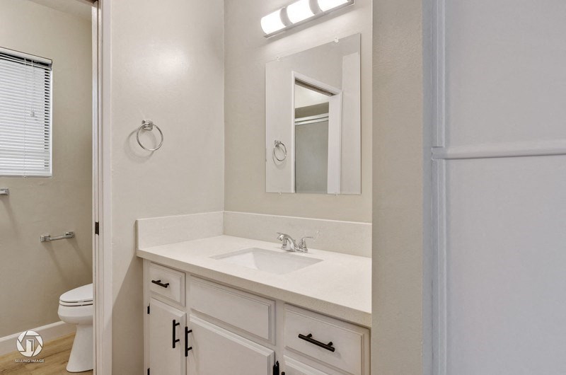 A white bathroom with a sink, mirror, and toilet.