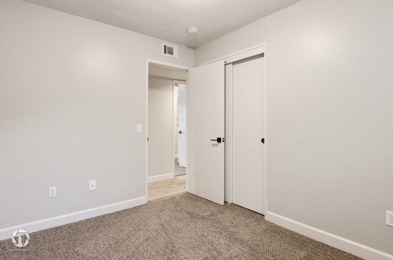 A room with a carpeted floor and two doors.