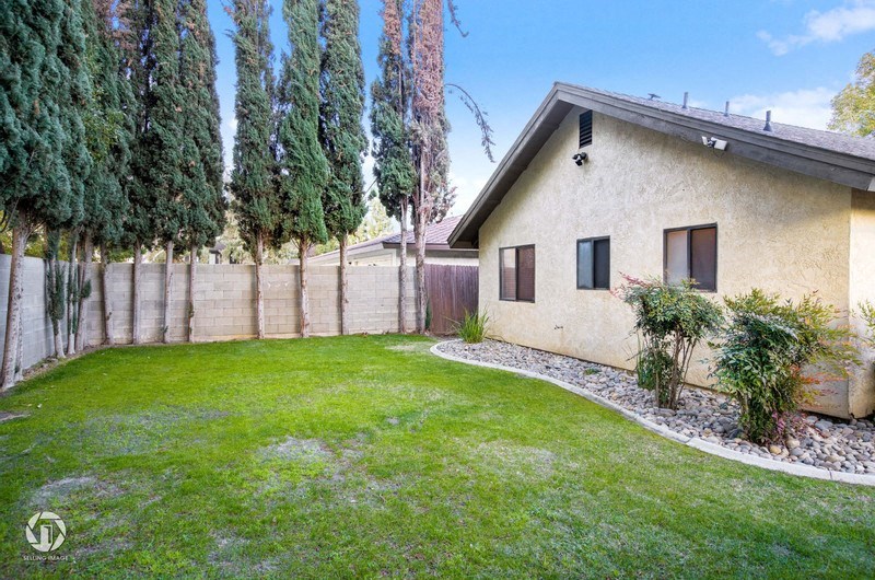 A house with a fence and trees in the background.