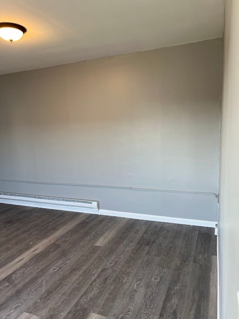 A room with a grey wall and a wooden floor.