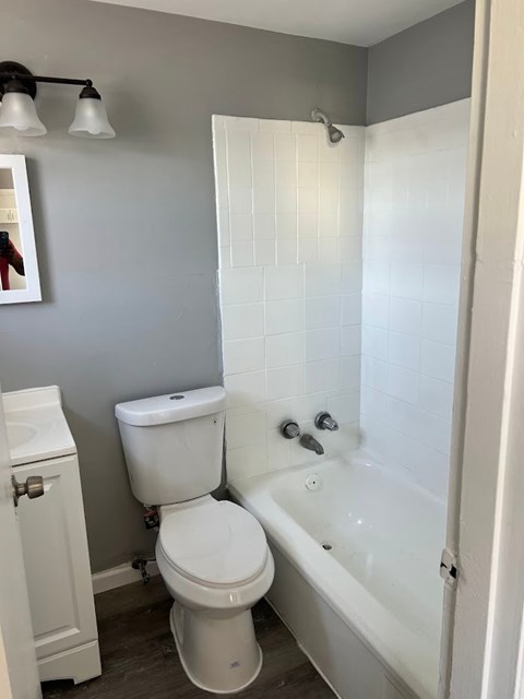 A white toilet sits next to a white bathtub in a bathroom.