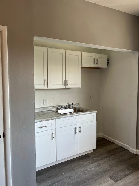 A kitchen with white cabinets and a marble countertop.