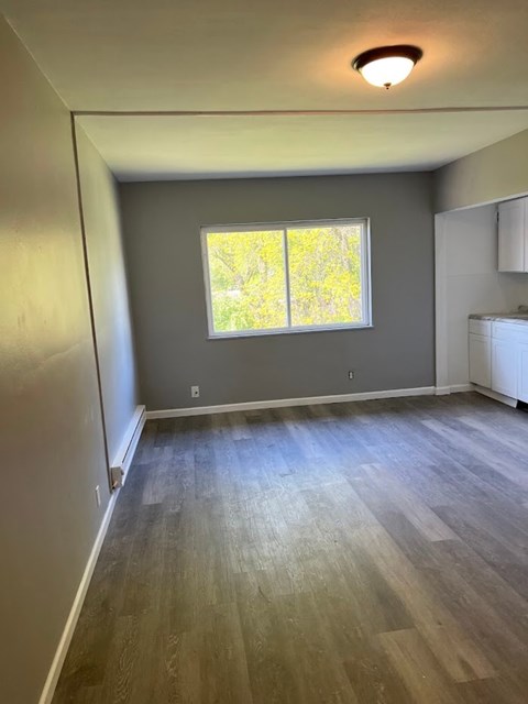 A room with a window and wooden flooring.