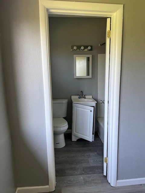 A bathroom with a toilet, sink and mirror.