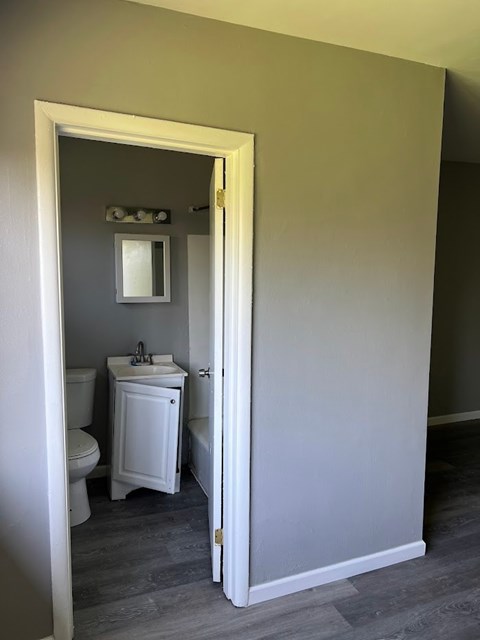 A bathroom with a toilet, sink and mirror.