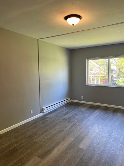 A room with a window and a wooden floor.