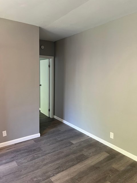 A room with a wooden floor and a doorway leading to another room.