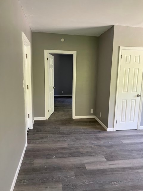 A hallway with a white door on the right and a black door in the middle.