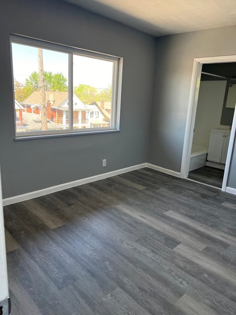 A room with grey flooring and a large window.