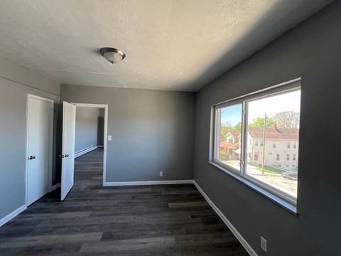 A room with a window and a view of a building outside.