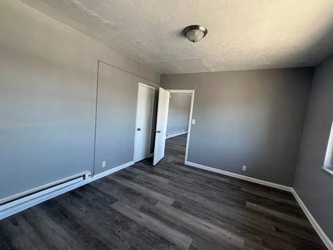 A room with grey walls and wooden flooring with a white door on the right.