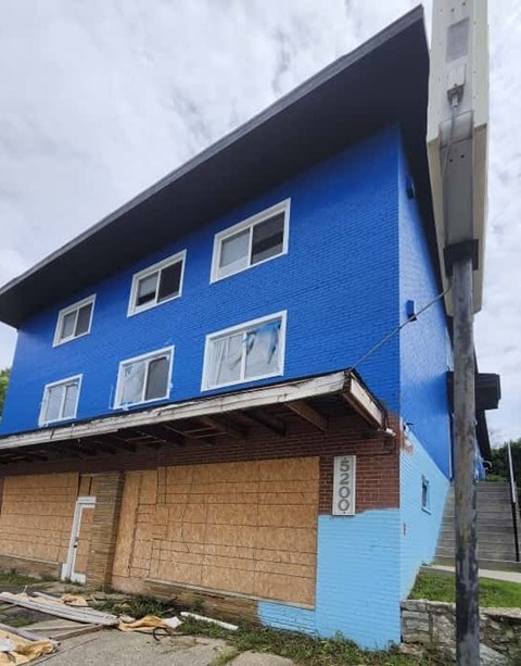 A blue building with boarded up windows.