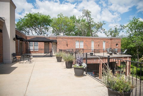 the yard of a brick building with patio furniture and plants