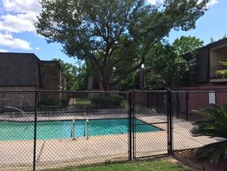 a swimming pool in front of a house with a fence