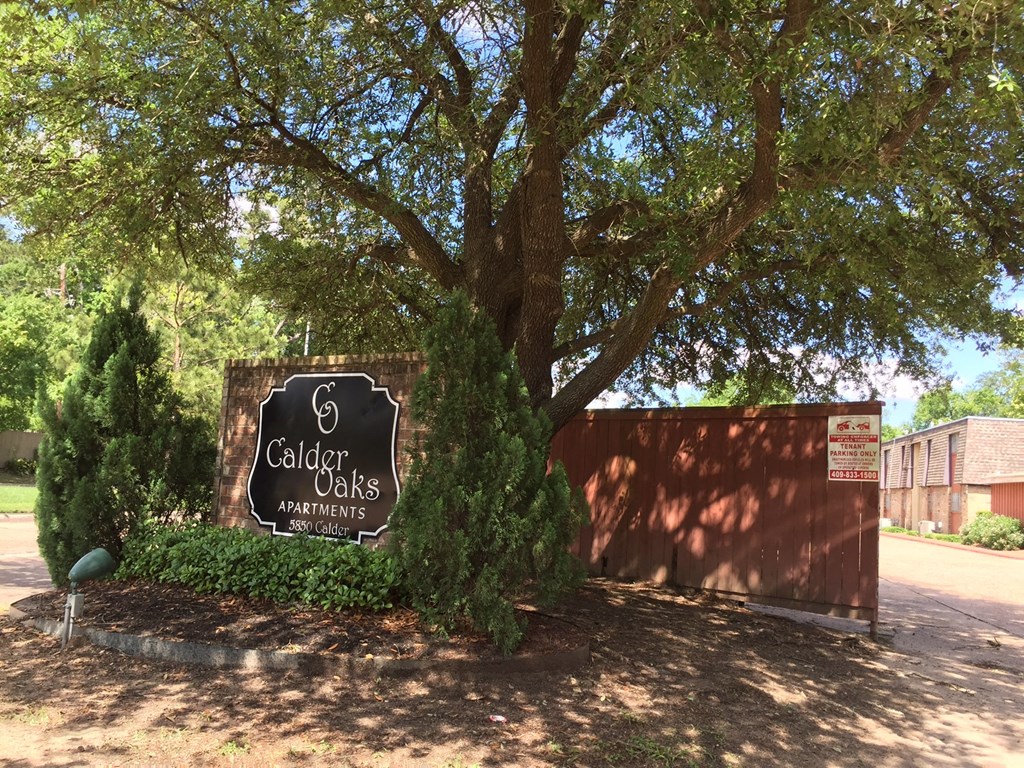 a sign oaks apartments in front of a tree
