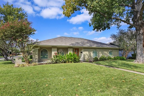 A house with a green lawn and trees in front.