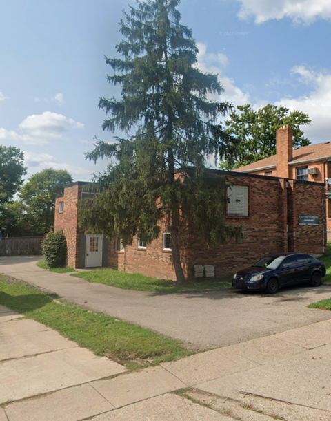 A black car is parked in front of a brick building.