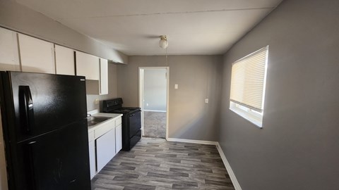 A kitchen with a black fridge and white cabinets.