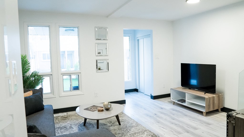 A living room with a black couch, a coffee table, and a television on a wooden stand.