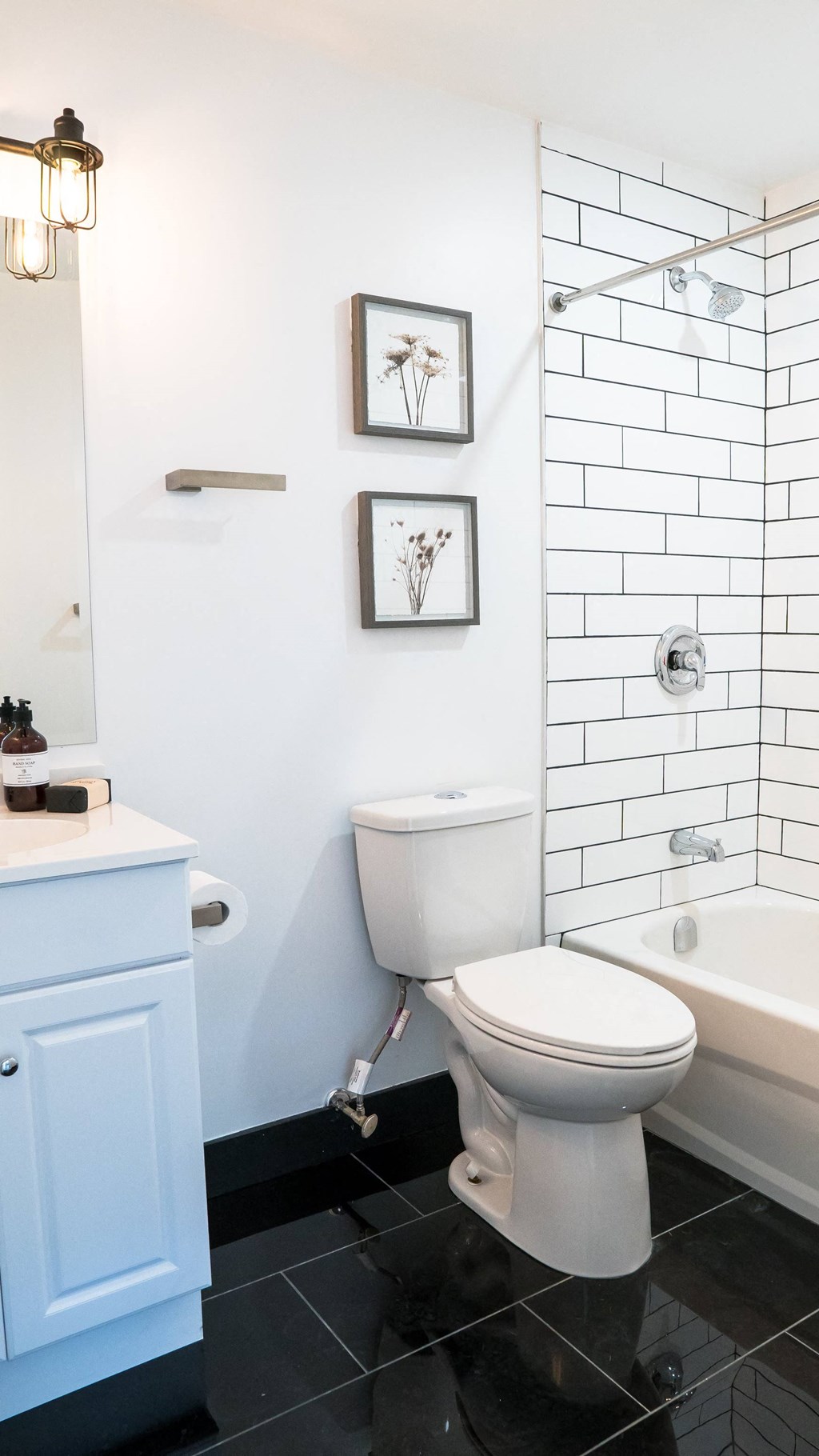A white toilet in a bathroom with a white tiled wall.