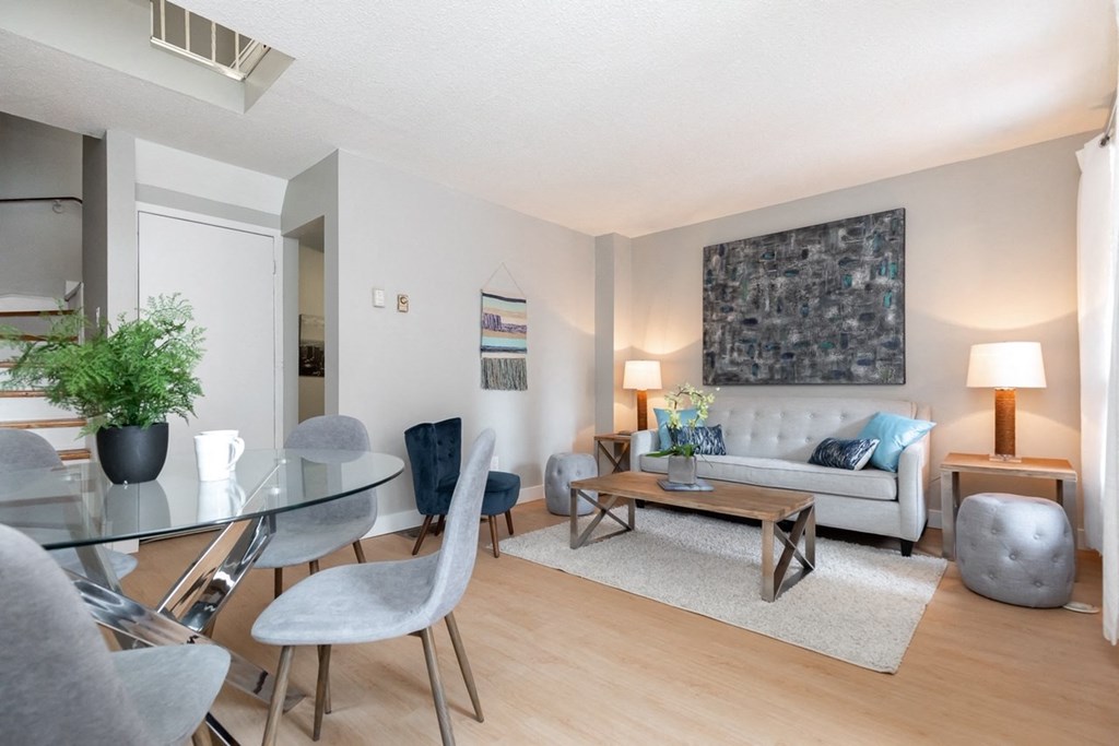 A modern living room with a glass table and grey chairs.