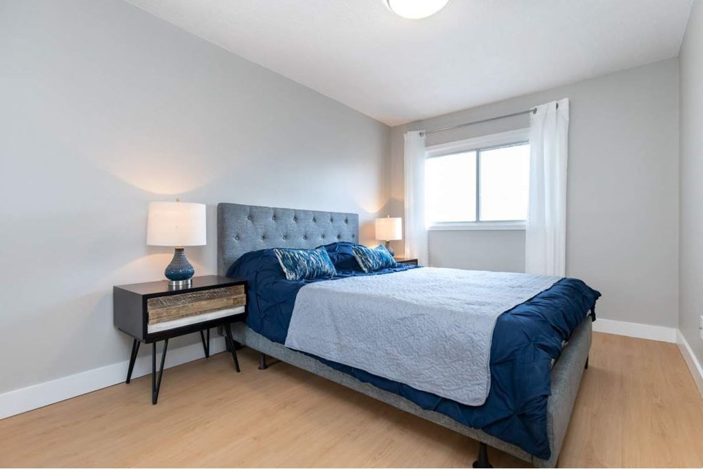 A bedroom with a bed, nightstand, and lamp.