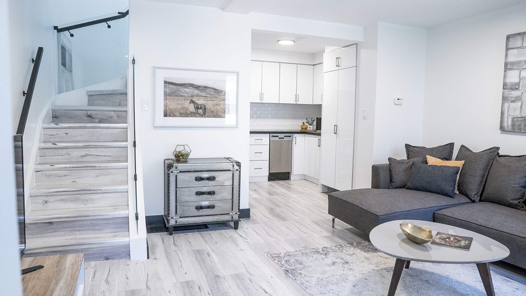 A modern living room with a grey sofa and a wooden staircase.