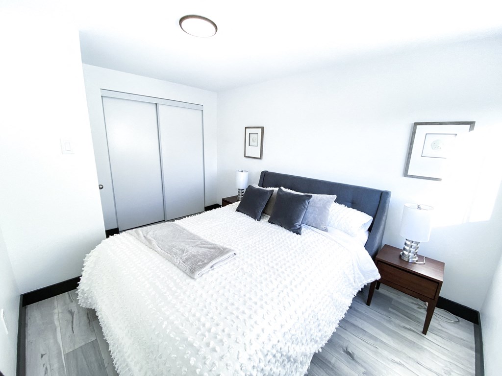 A bedroom with a bed, nightstand, and picture frames.