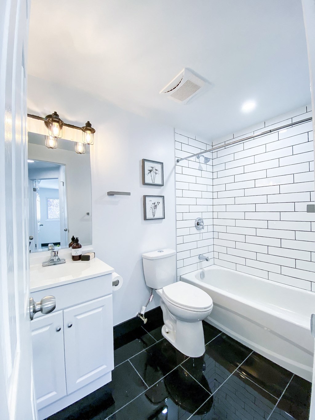 A white bathroom with a black tile floor.
