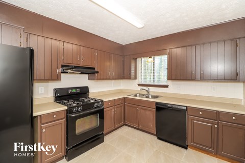 A kitchen with brown cabinets and a black refrigerator.
