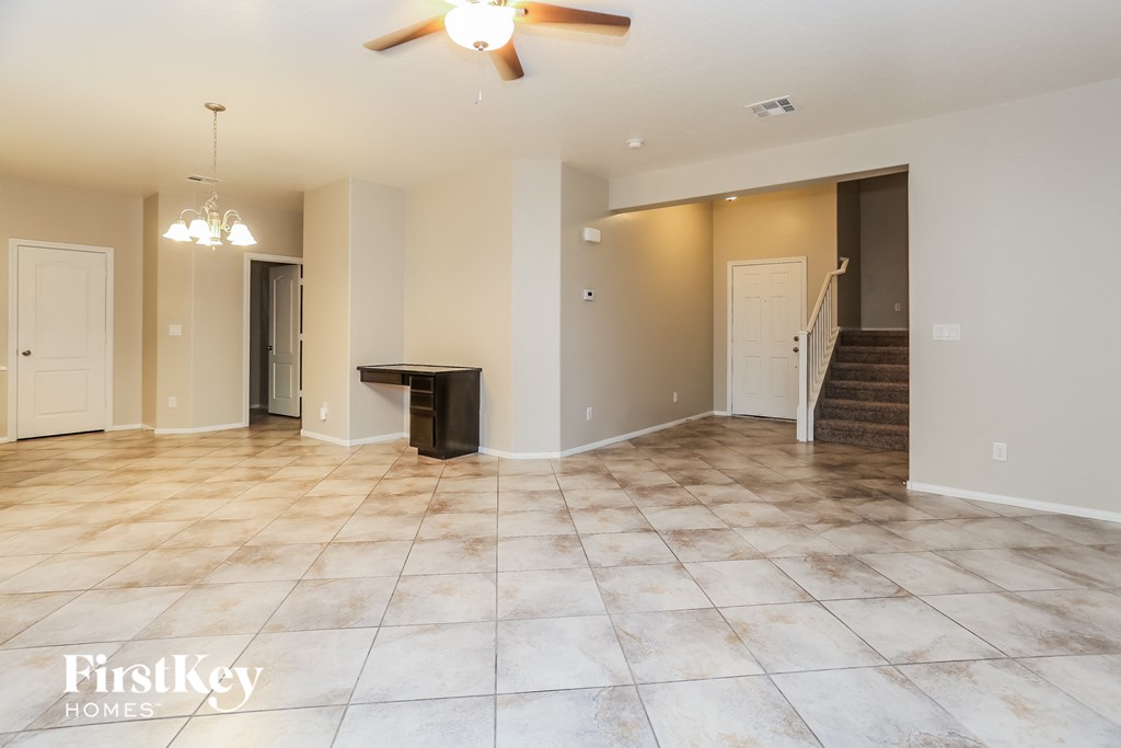 A spacious room with a tiled floor and a ceiling fan.