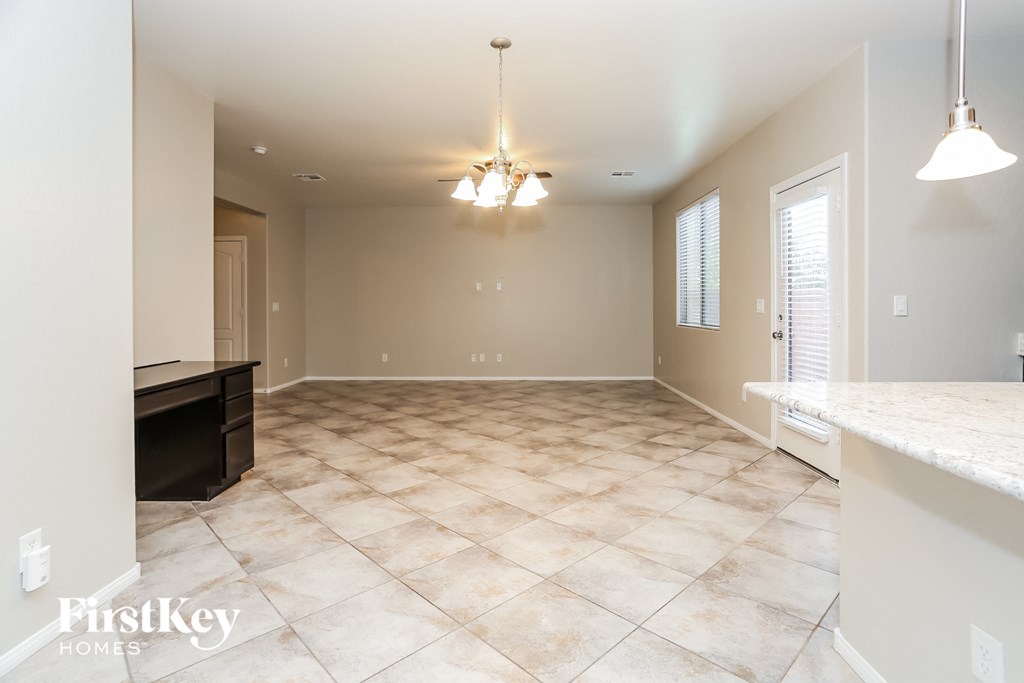 A spacious room with a tiled floor and a chandelier hanging from the ceiling.