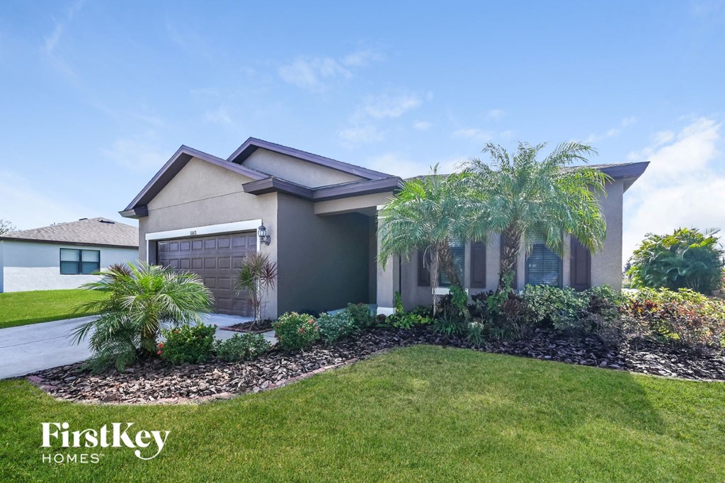 a house with a lawn and palm trees in front of it