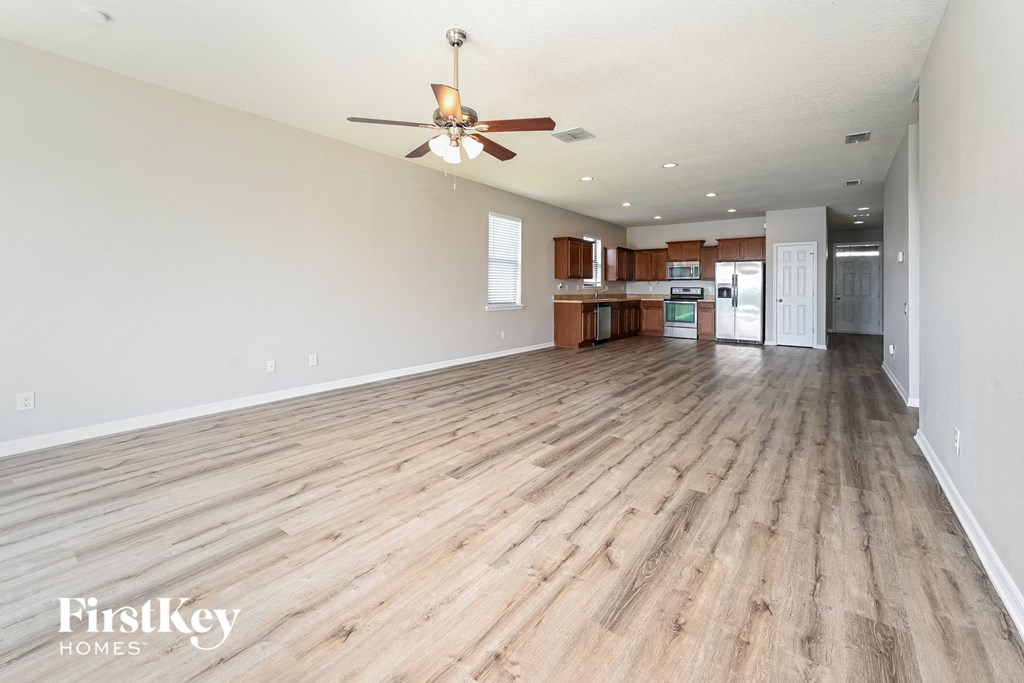 an empty living room with wood flooring and a ceiling fan