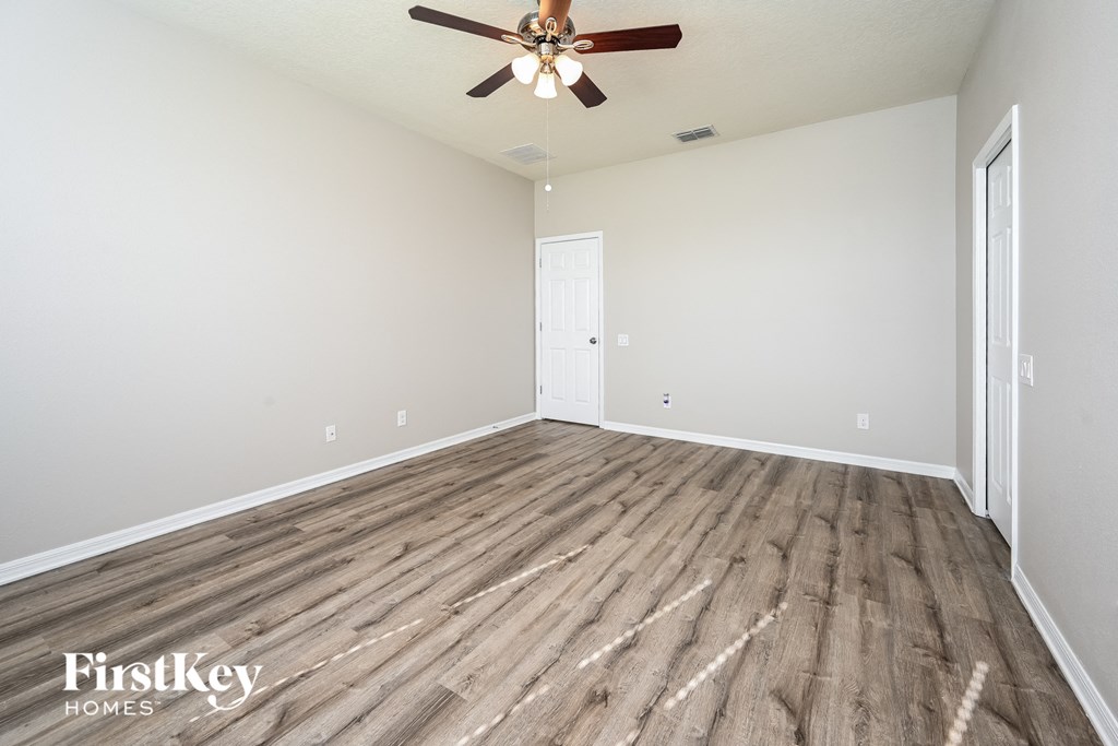 the spacious living room with hardwood flooring and a ceiling fan